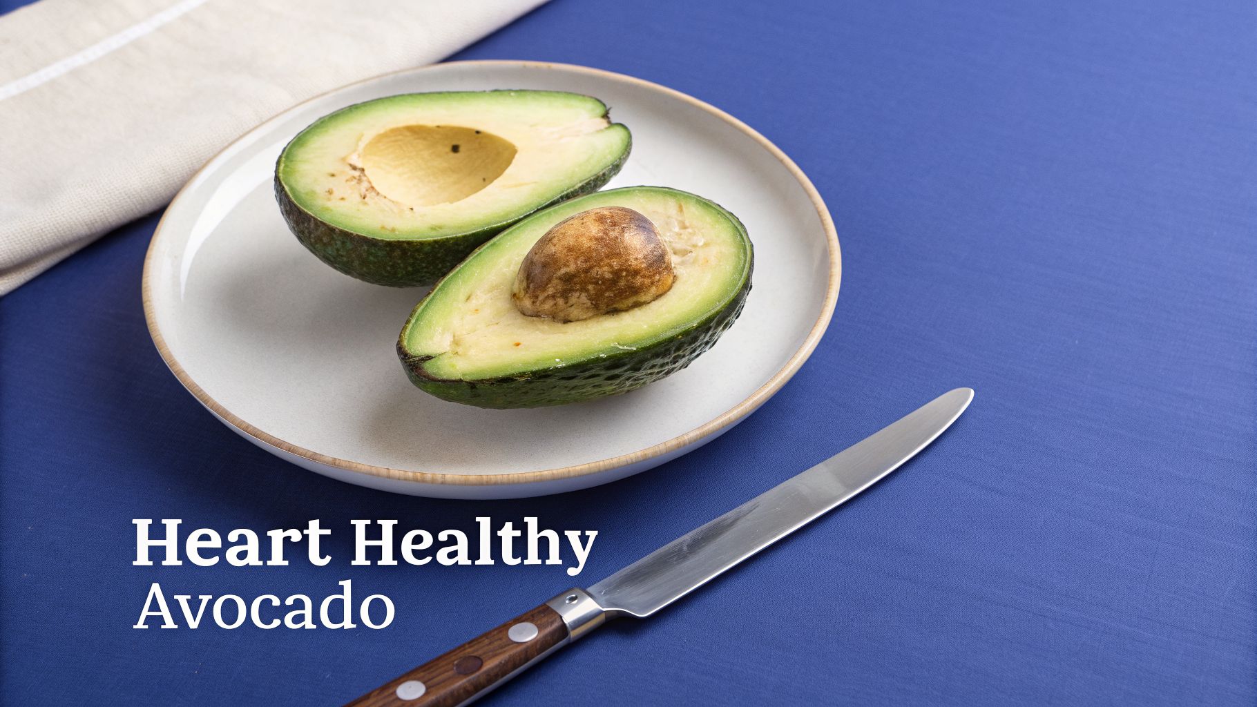 The Top 10 Foods with Fibre for Optimal Health in 2026 3 Two halves of a ripe avocado on a white plate with a knife on a blue surface, highlighting its heart-healthy benefits.
