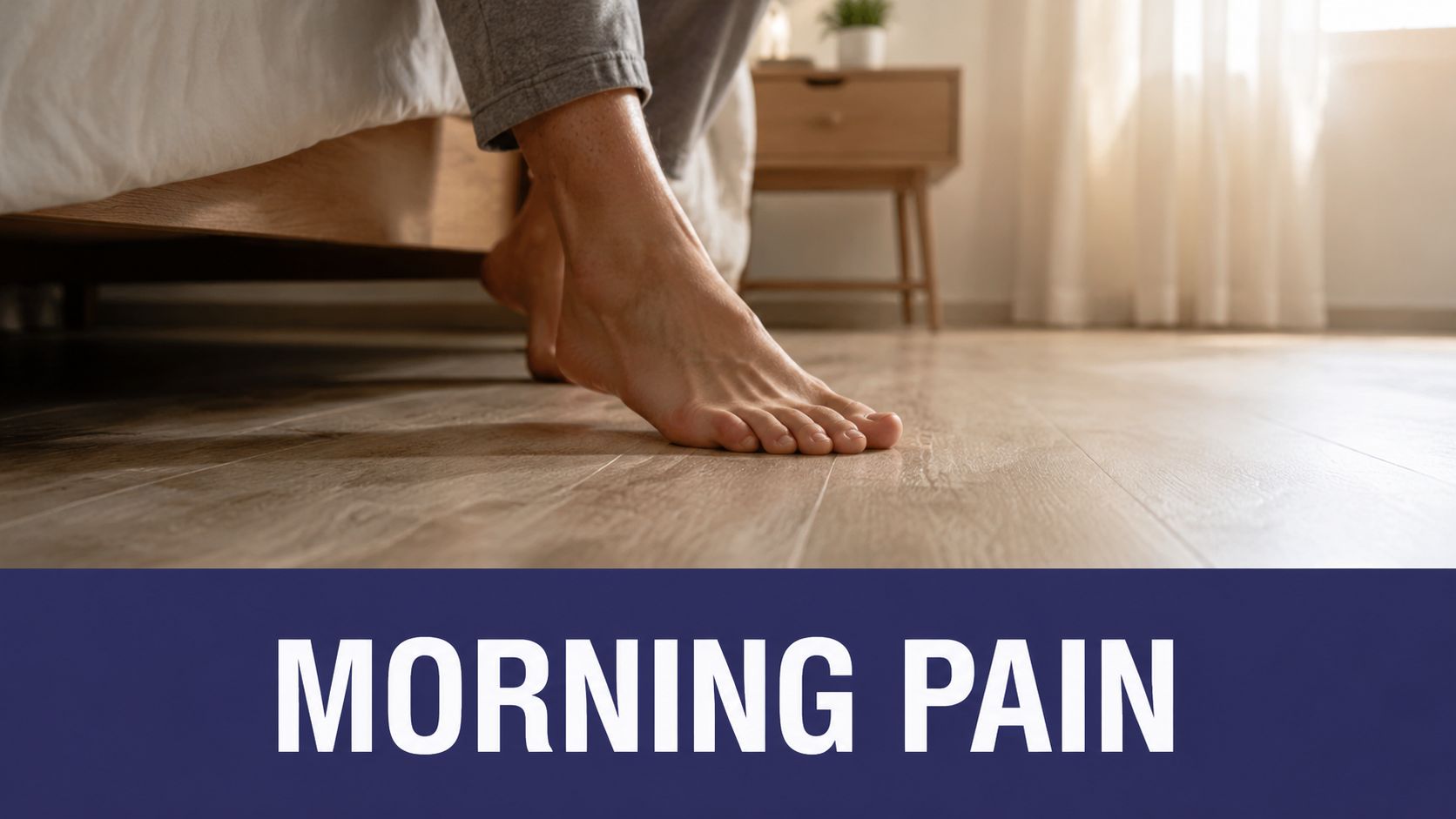 A person sitting on the edge of a bed, putting their bare feet on the wooden floor.